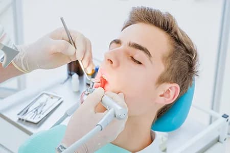 Photo of patient receiving dental treatment while seated in a dental chair