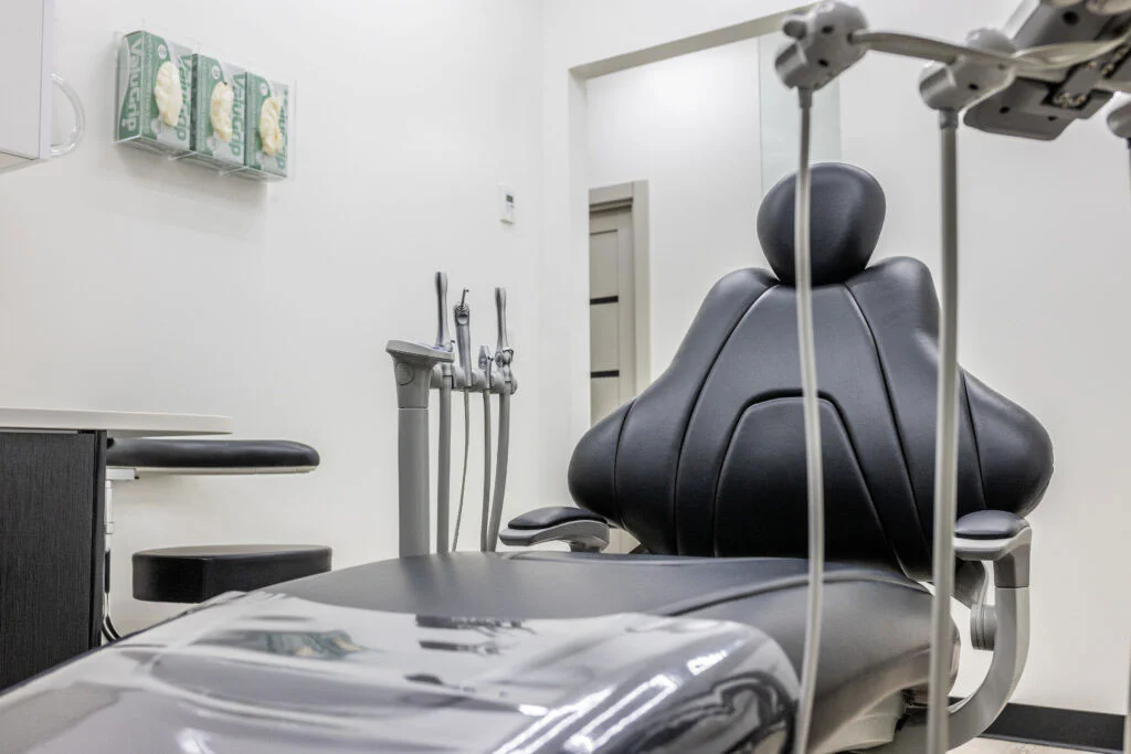 Modern dental treatment room with black patient chair dental tools and clean white walls prepared for all on four dental implants astoria procedure